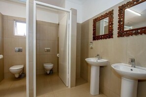A bathroom with two toilets, two sinks, and a mirror with an ornate frame. - Umhlanga Backpackers (Umhlanga)
