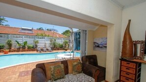 Una sala de estar con sofá, piscina y vistas al exterior.