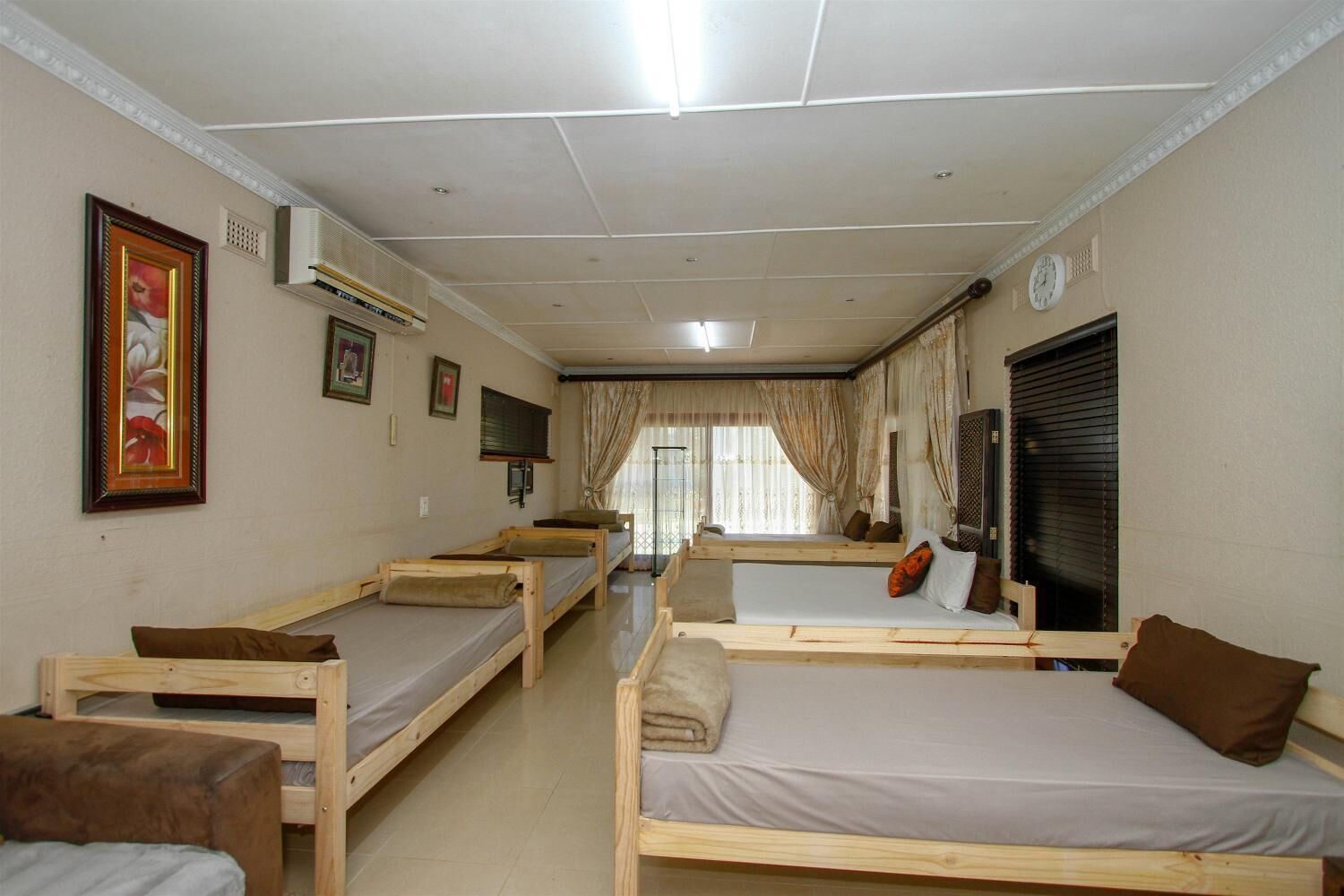 A dormitory room with bunk beds, a television, and a window with curtains.