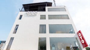 A modern building with a white facade, multiple windows, and a prominent red sign with the name "OYO". - OYO Flagship 1348 Hotel Home Anaya (Medan)