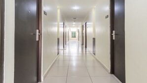A long, well-lit hallway with doors on both sides, leading to a bright room at the end. - OYO Flagship 1348 Hotel Home Anaya (Medan)