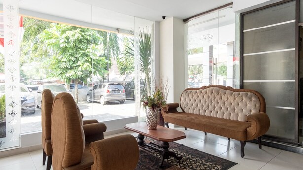 A lobby with a sofa, chairs, a coffee table, and a vase with plants. - OYO Flagship 1348 Hotel Home Anaya (Medan)