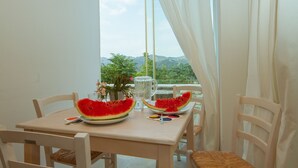 A table with two plates of watermelon, a pitcher, and a glass on a balcony with a view of mountains. - Thyone Uno Cottage (Vavla)