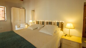 A bedroom with a large bed, bedside tables, a wardrobe, and a mirror. - Thyone Uno Cottage (Vavla)