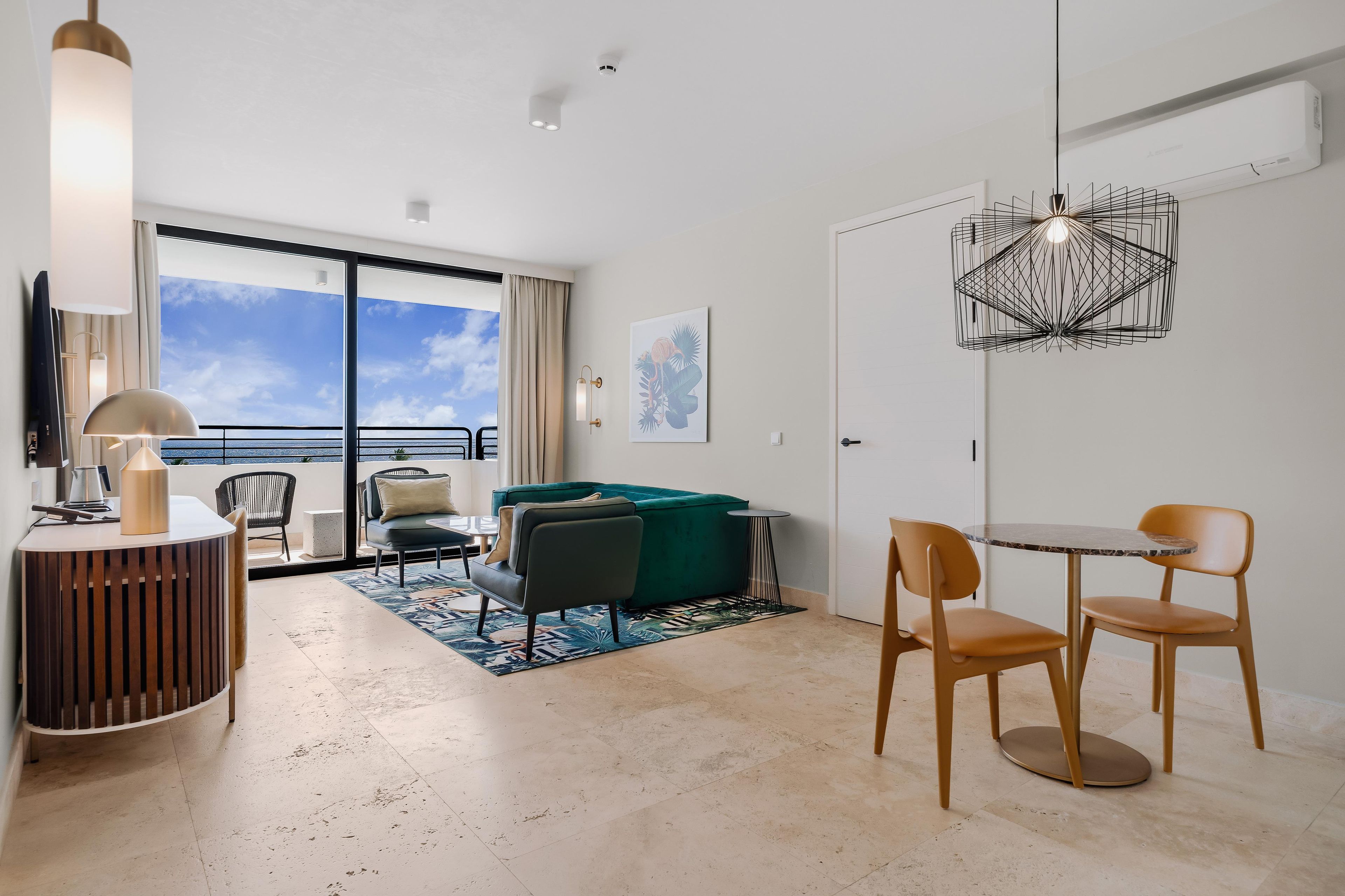 Ein modernes Wohnzimmer mit einem grünen Sofa, einem Esstisch mit Stühlen, einem großen Fenster mit Blick und einem einzigartigen geometrischen Pendel.