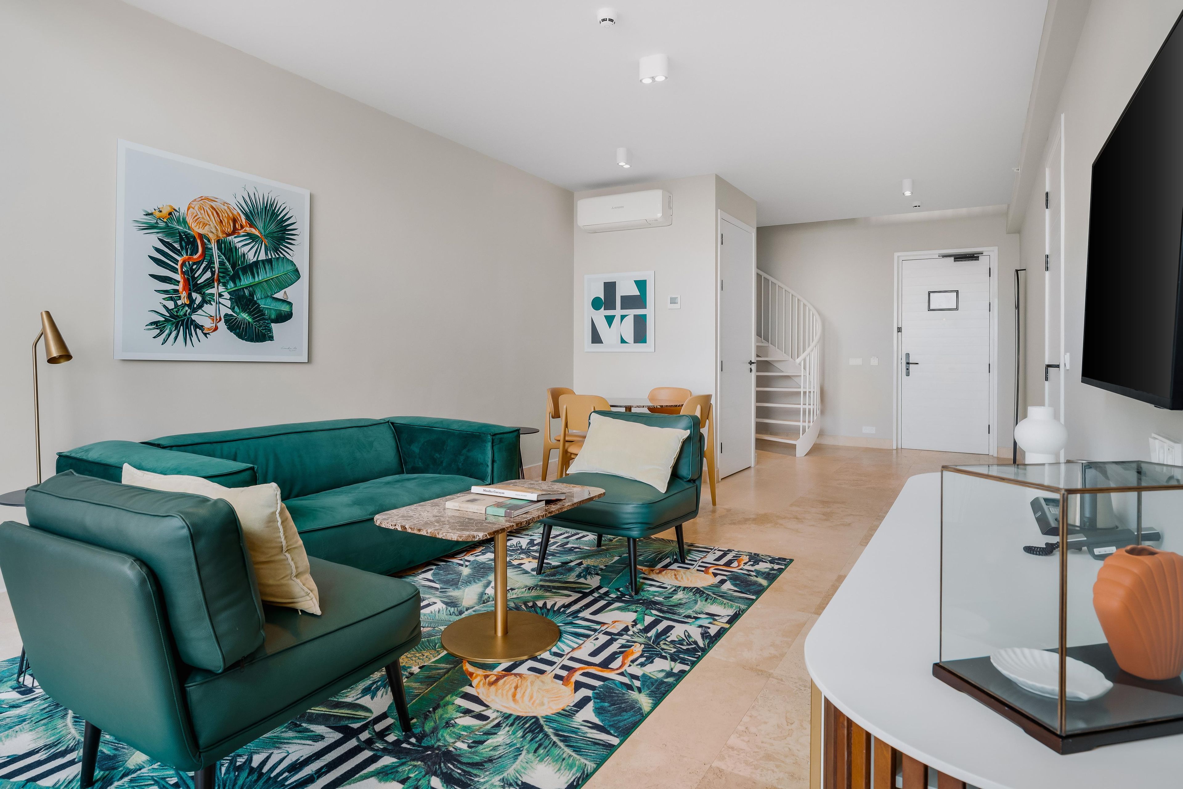 A modern living room with a teal sofa, a coffee table, and a patterned rug.