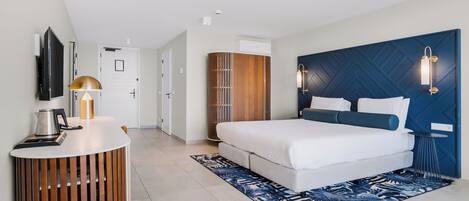 Une chambre d’hôtel moderne équipée d’un lit, d’une table de chevet en bois, d’une télévision et d’une armoire.