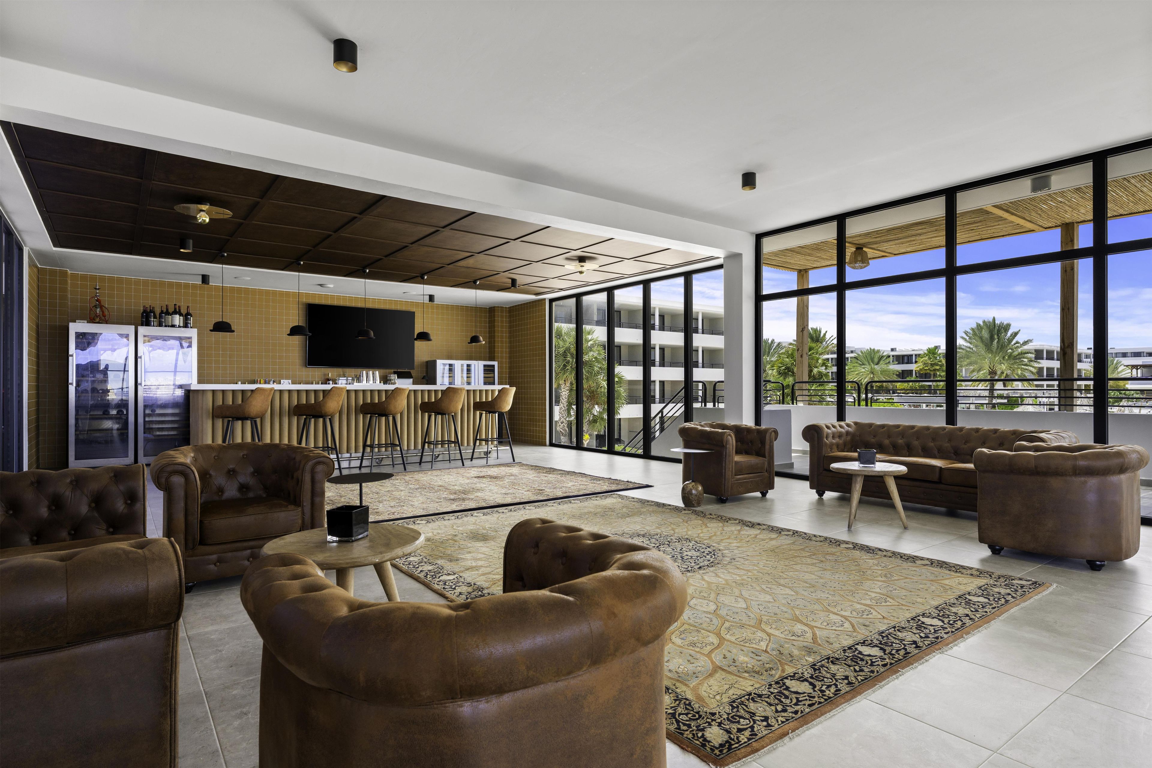 A modern interior with a bar area, seating, and large windows offering a view.