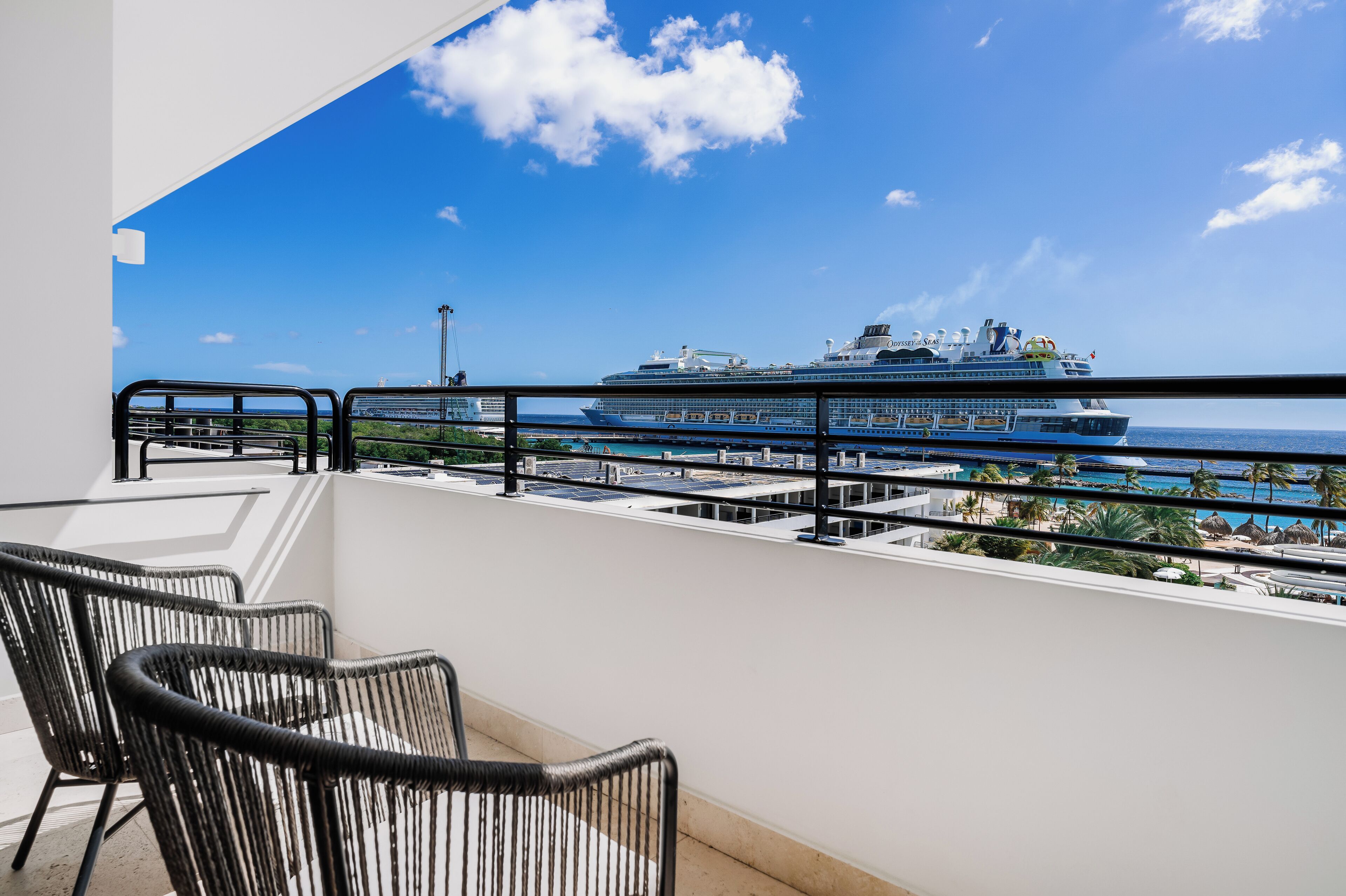 Un balcón con vista a un crucero y una playa.