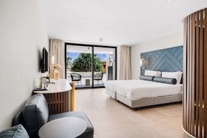 A modern hotel room with a large bed, a seating area with a table, and a view of the outdoors. - Mangrove Beach Corendon Curacao All-Inclusive Resort, Curio by Hilton (Willemstad)