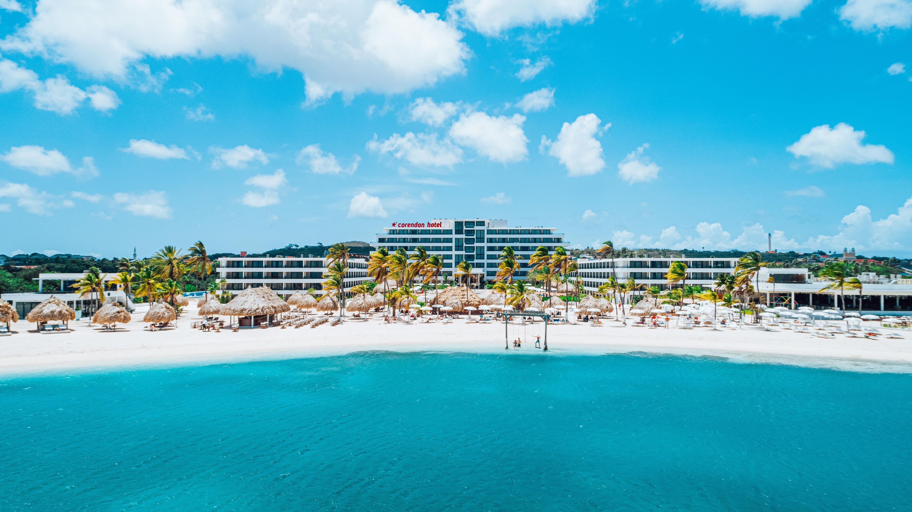 Un hotel con vista a la playa, palmeras y cielo despejado.