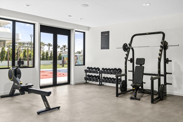 A gym with exercise equipment, large windows, and a view of a sports field. - Mangrove Beach Corendon Curacao All-Inclusive Resort, Curio by Hilton (Willemstad)
