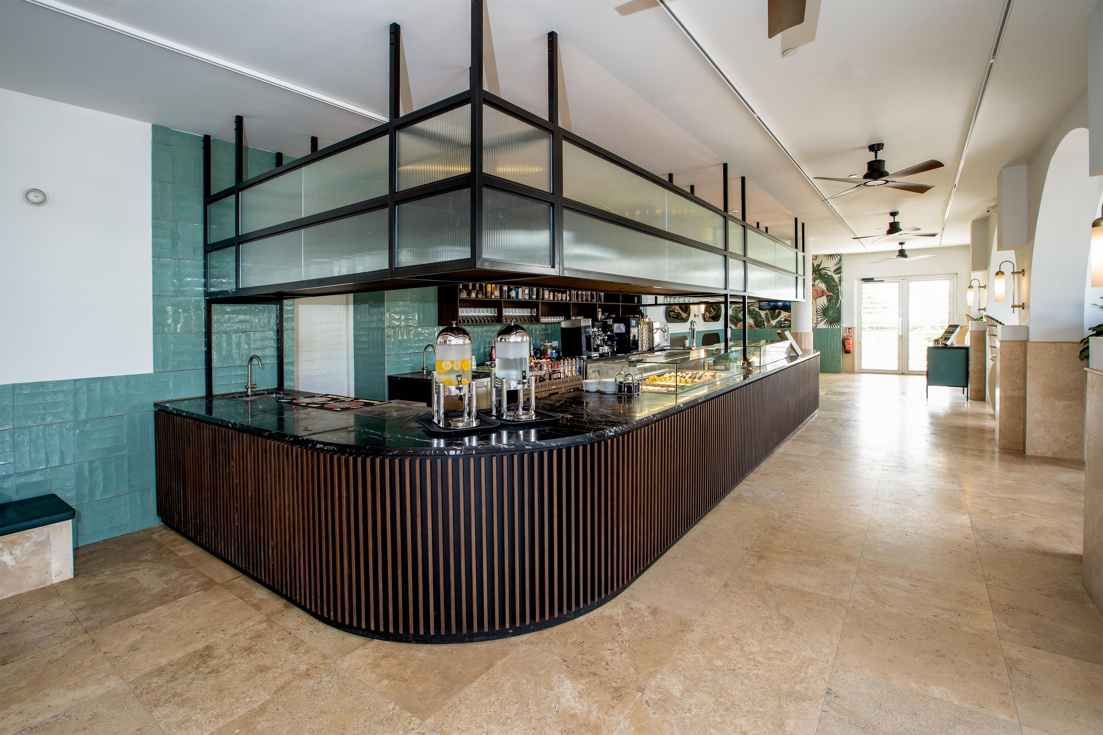 Eine Bar mit einer gebogenen Theke, einer Kaffeemaschine und einer Auswahl an Getränken.
