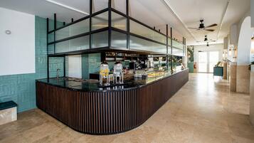 Eine Bar mit einer gebogenen Theke, einer Kaffeemaschine und einer Auswahl an Getränken.