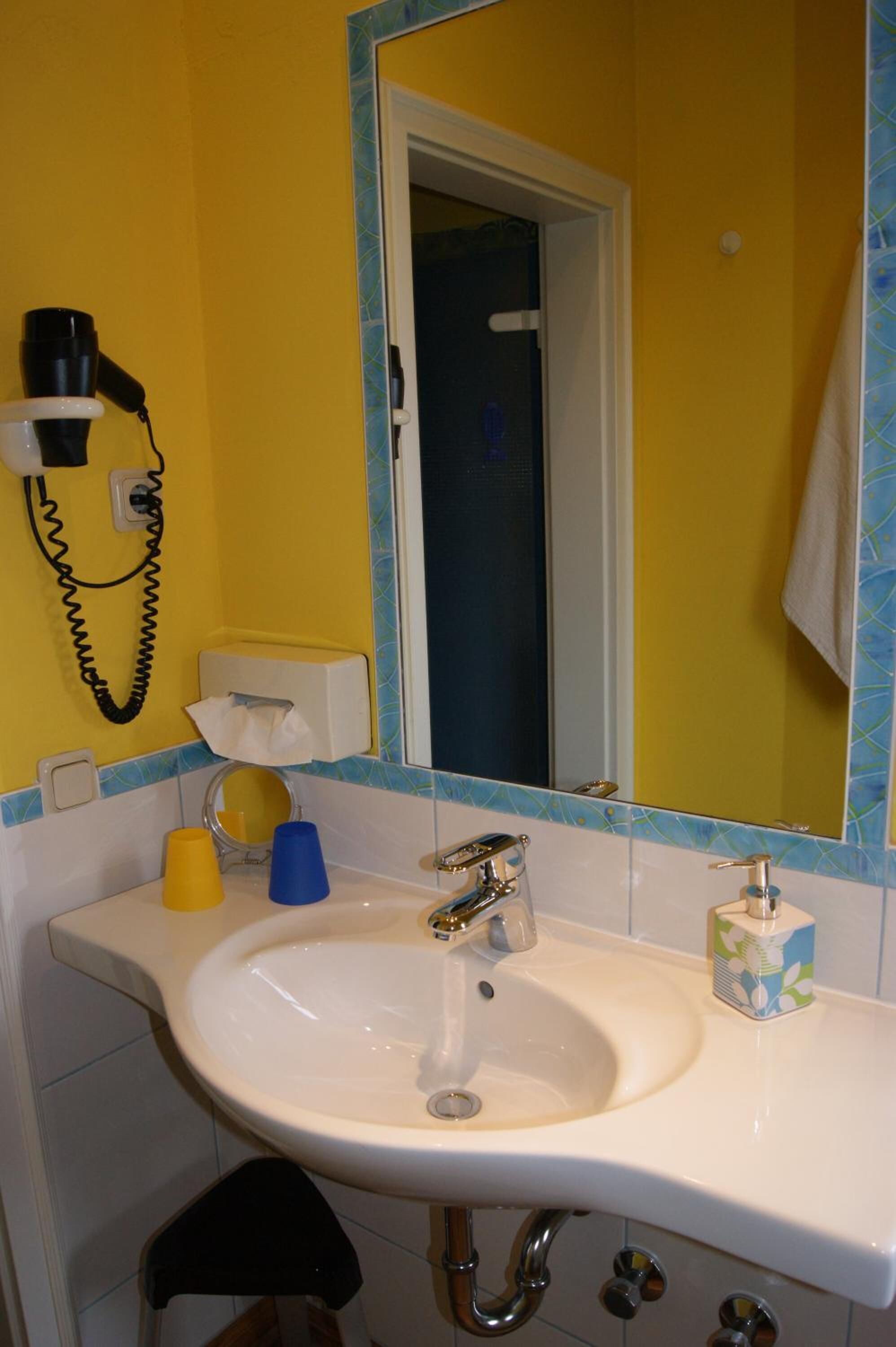 Un baño con un lavamanos blanco, un espejo, una toalla colgada en la pared y un inodoro.