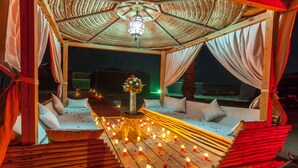 A wooden deck with a canopy, candles, and a floral arrangement. - Lemnaouar Erg Camp (Rissani)