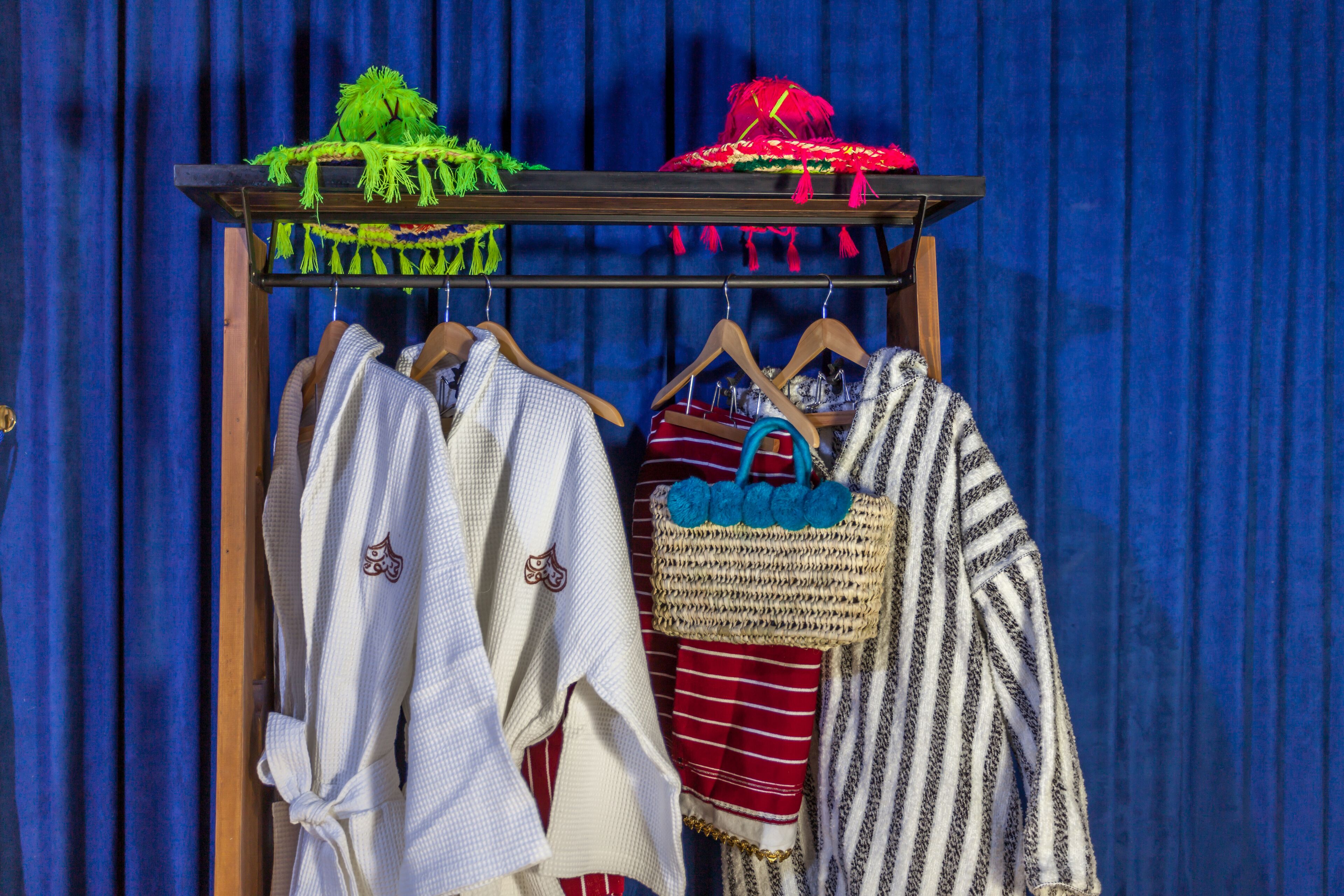 A rack with various garments including a striped sweater, a white robe, and a red and white striped garment.