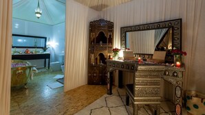 A room with a traditional wooden cabinet, a mirror, and a small table with candles. - Lemnaouar Erg Camp (Rissani)