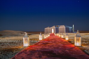 Un paisaje desértico con una alfombra roja que conduce a un edificio de múltiples puertas.