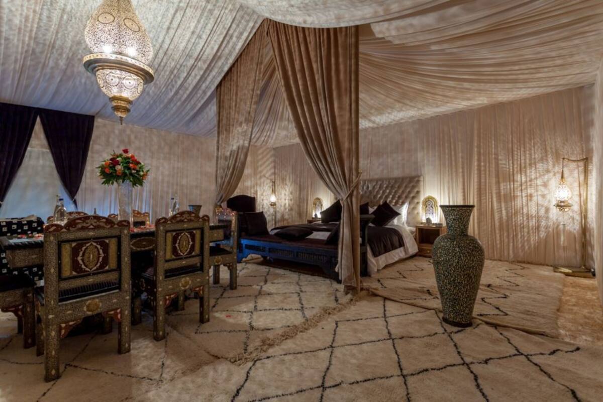A luxurious room with a bed, a large vase, and a chandelier.