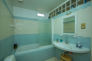 A bathroom with a bathtub, a sink, and a mirror. - Villa Anasia (Paralimni)