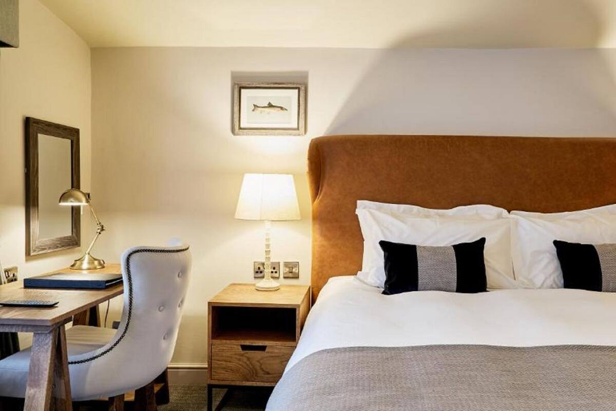 A hotel room with a large bed, a desk, a chair, and two bedside lamps.