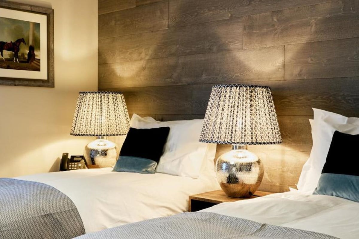 Une chambre d’hôtel avec deux lits, chacun étant équipé d’une lampe et d’un téléphone sur une table de chevet.