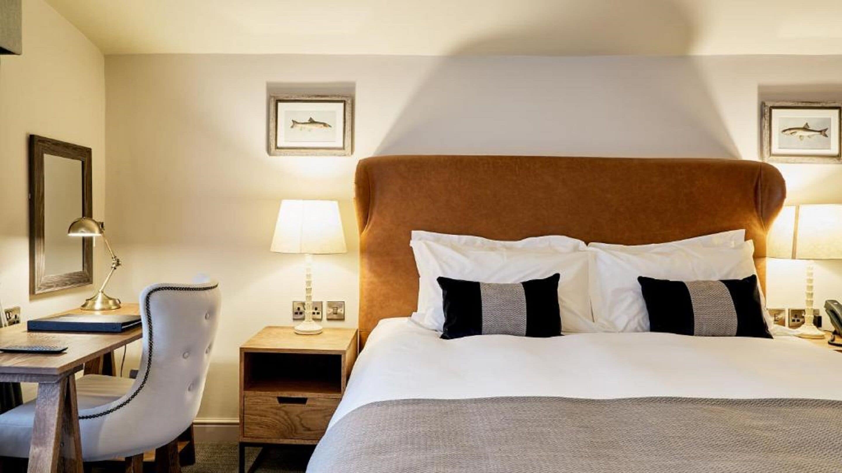 Habitación de hotel con una cama grande, dos lámparas de noche, un escritorio con una silla y cuadros en la pared.