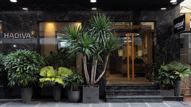 The exterior of Hadiva Boutique Hotel with a modern facade, large potted plants, and a well-lit entrance. - Hadiva Boutique Hotel (Da Nang)