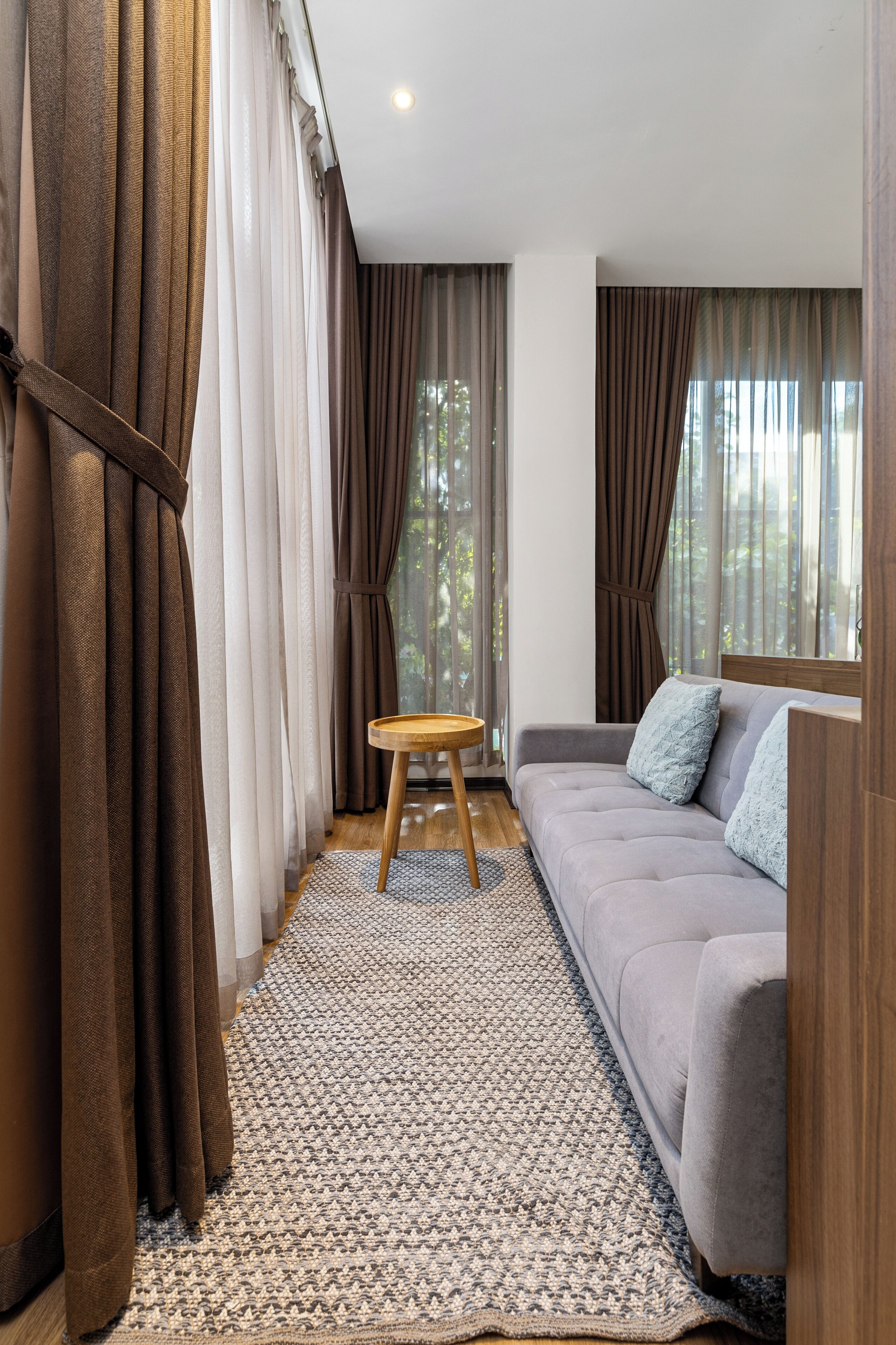 A modern living room with a grey sofa, a small wooden table, and a patterned rug.
