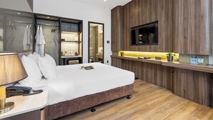 A modern hotel room with a large bed, a desk with a lamp, a TV mounted on the wall, and a wooden panel design. - Hadiva Boutique Hotel (Da Nang)