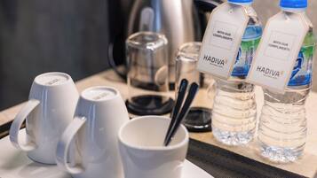 Un desayuno con tazas blancas, un vaso, una cuchara y dos botellas de agua con la etiqueta "HADIVA".