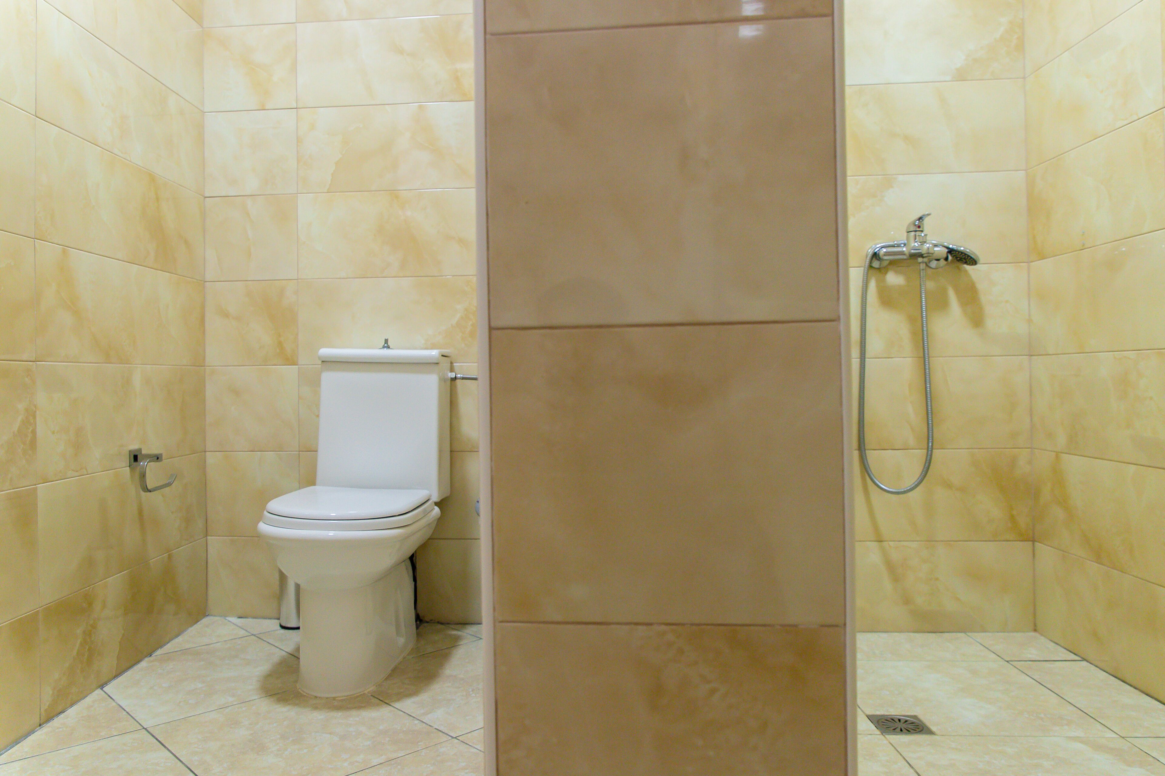 A bathroom with a toilet, a shower, and tiled walls.