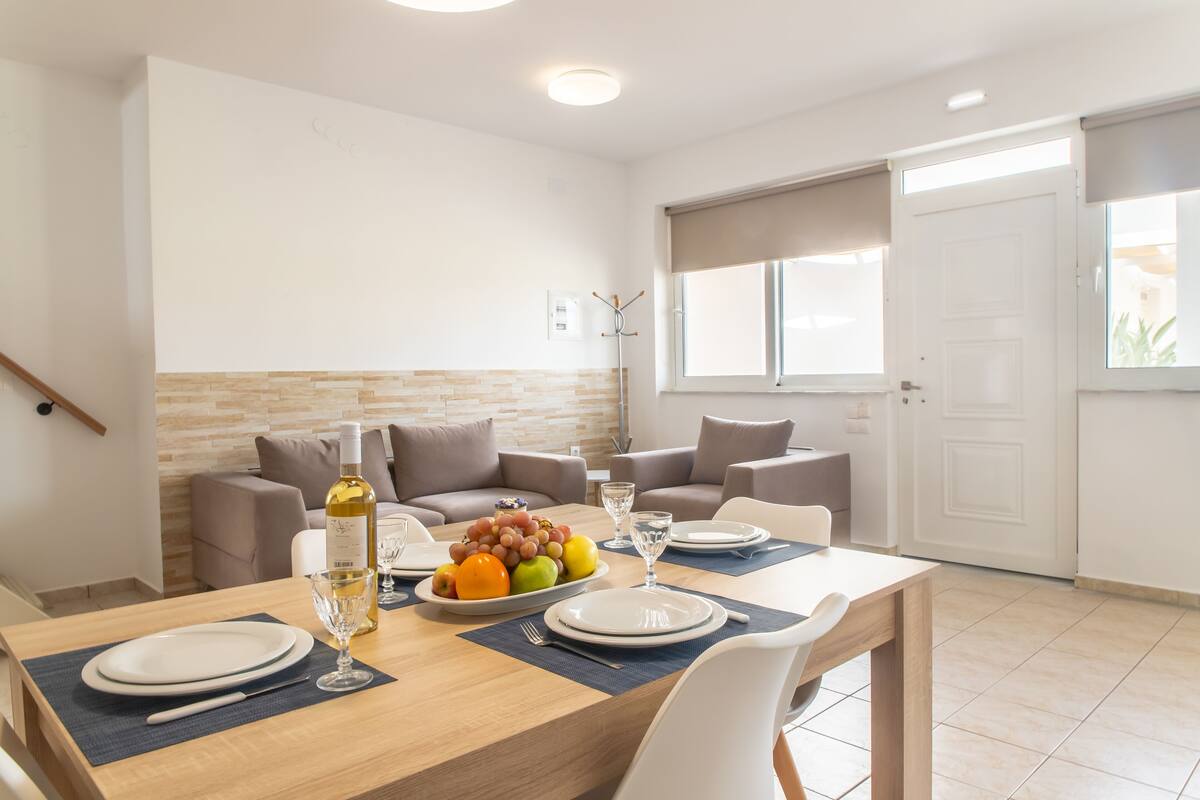 A dining area with a wooden table set for four, surrounded by beige sofas.