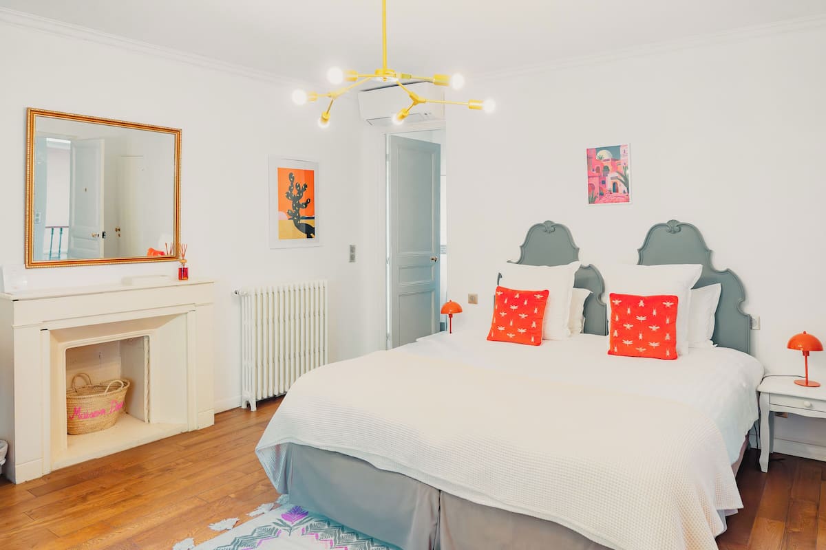 Un dormitorio con una cama grande, un espejo, un radiador y una mesita con una lámpara.