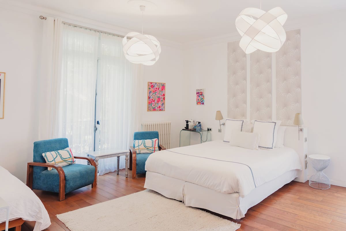 Un dormitorio con una cama grande, dos sillones, una mesita y un radiador.