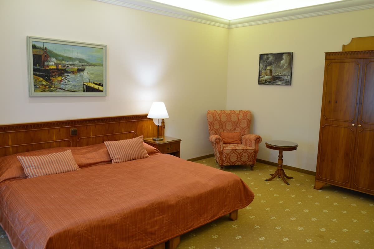 Une chambre d’hôtel avec un grand lit, une chaise, une petite table et un placard.