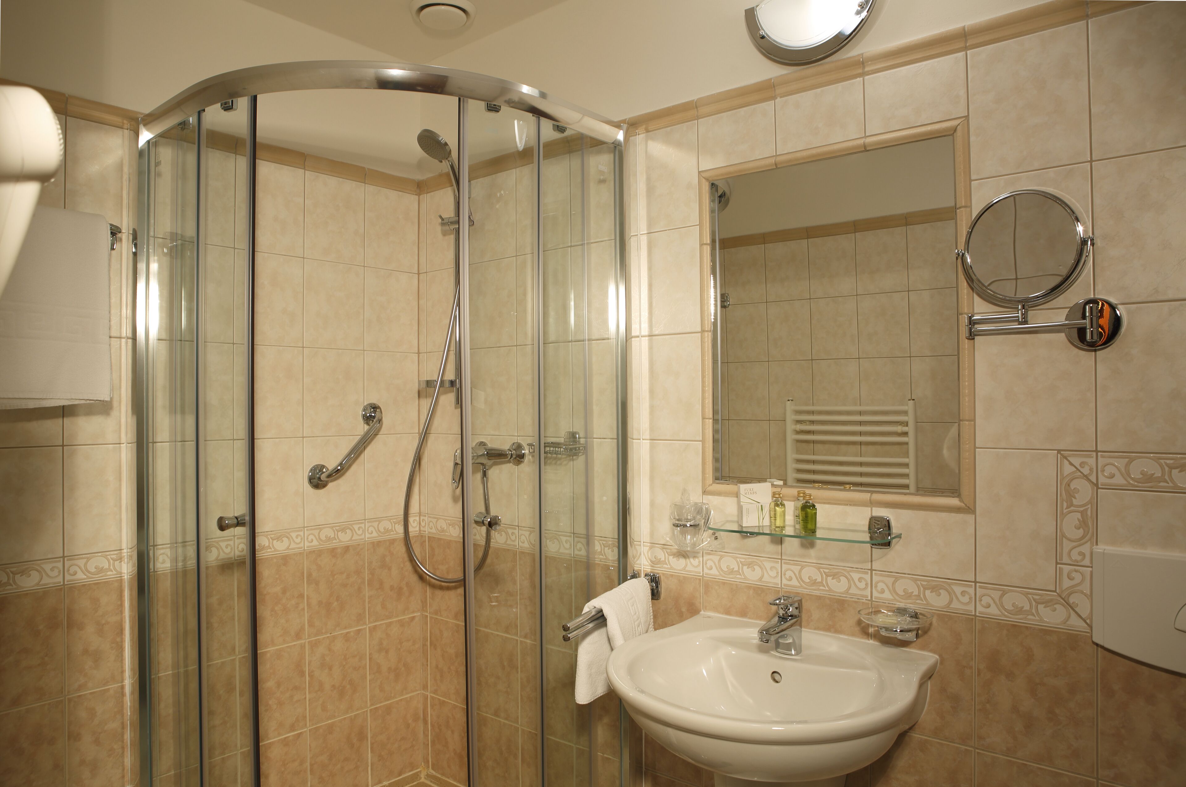 A modern bathroom with a glass-enclosed shower, a sink, and a mirror.