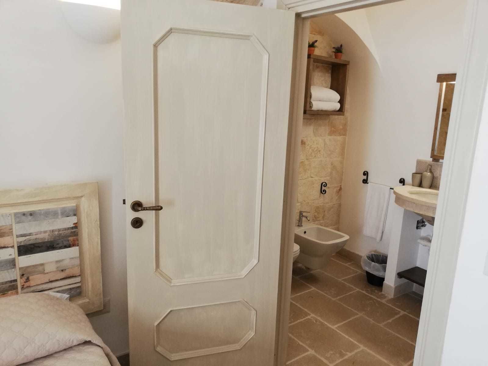 A bedroom with a bed, a door leading to a bathroom with a sink, toilet, and shower.