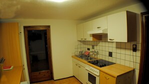 A compact kitchen with a stove, sink, and cabinets. - Haus Zentral (Sankt Anton am Arlberg)