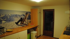 A compact kitchen with a wooden countertop, a refrigerator, and a door with a glass panel. - Haus Zentral (Sankt Anton am Arlberg)