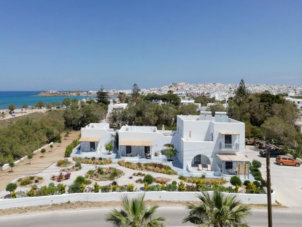 A coastal property with white buildings, a clear view of the sea, and a well-maintained garden.