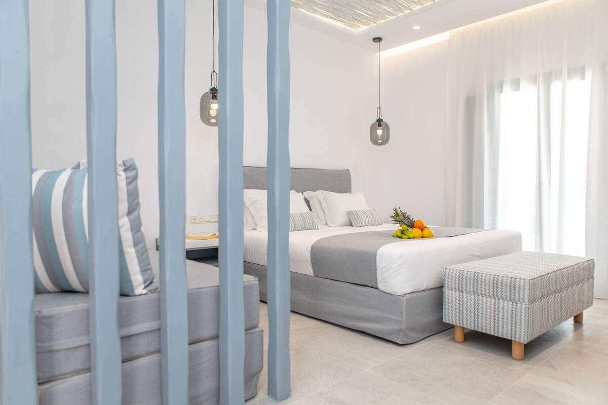 A modern bedroom with a bed, bedside tables, a hanging light fixture, and a window with curtains.