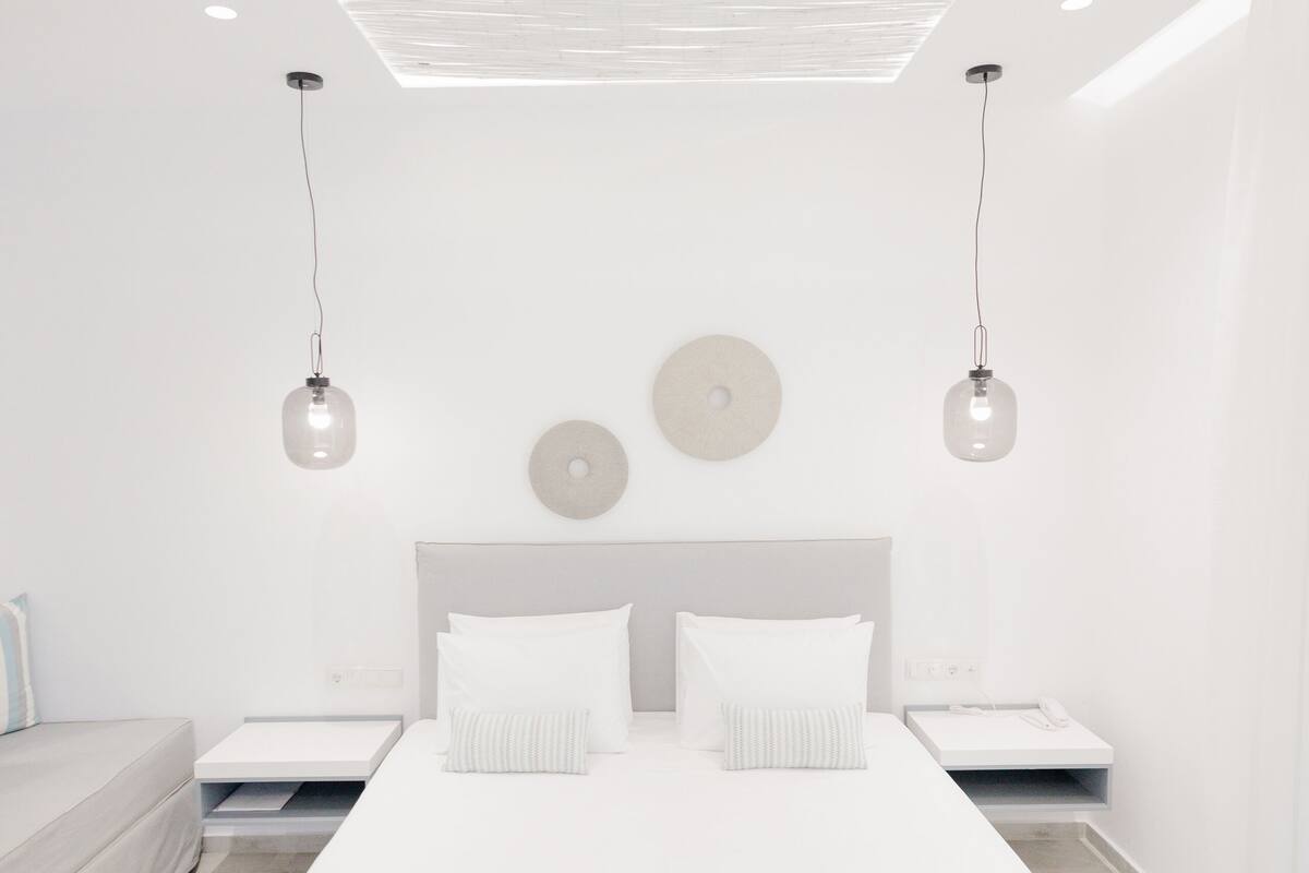 A modern bedroom with a large bed, two bedside tables, and a ceiling light fixture.