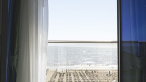 Vista desde un edificio alto con vista a una playa, con hileras de sombrillas y algunas personas.