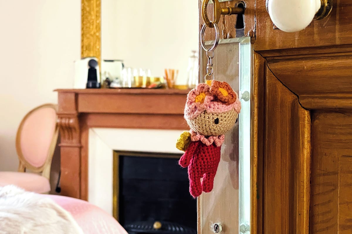 Un porte-clés orné d’une petite figurine en crochet, accrochée à une serrure de porte.