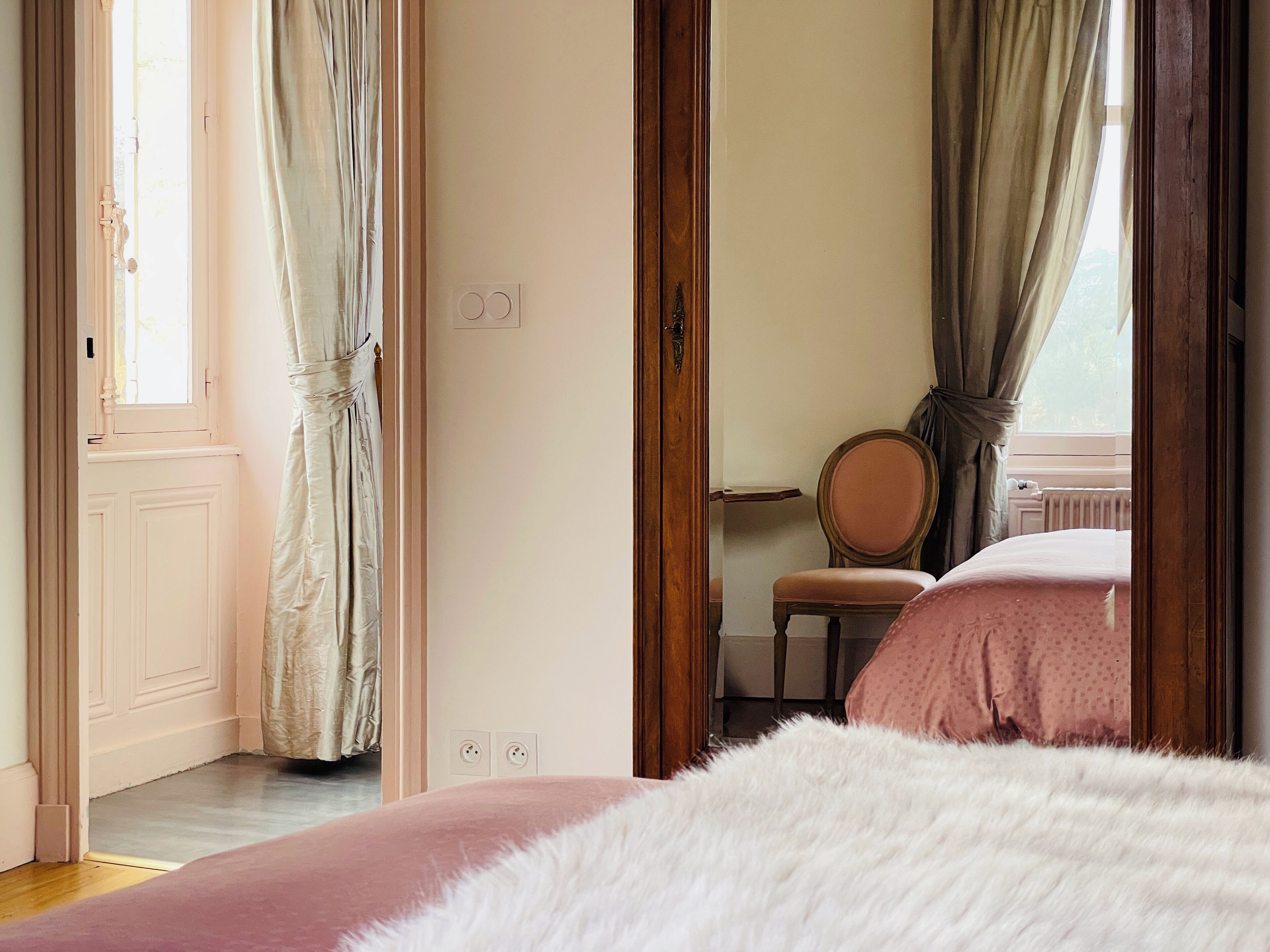 Ein Schlafzimmer mit einem Bett, einem Sessel und einem Fenster mit Vorhängen.