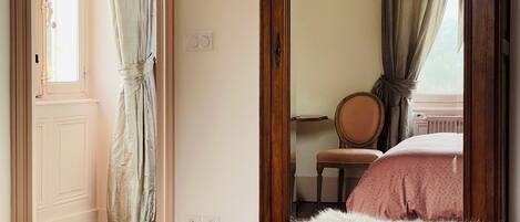 Ein Schlafzimmer mit einem Bett, einem Sessel und einem Fenster mit Vorhängen.