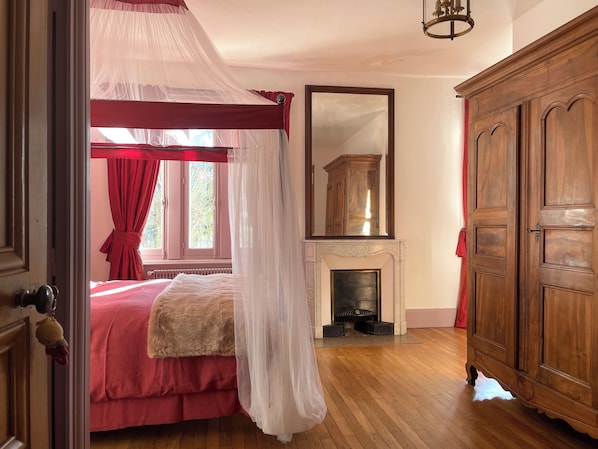 A bedroom with a four-poster bed, a fireplace, and a large mirror. - Le Clos des Fayettes (Theizé)