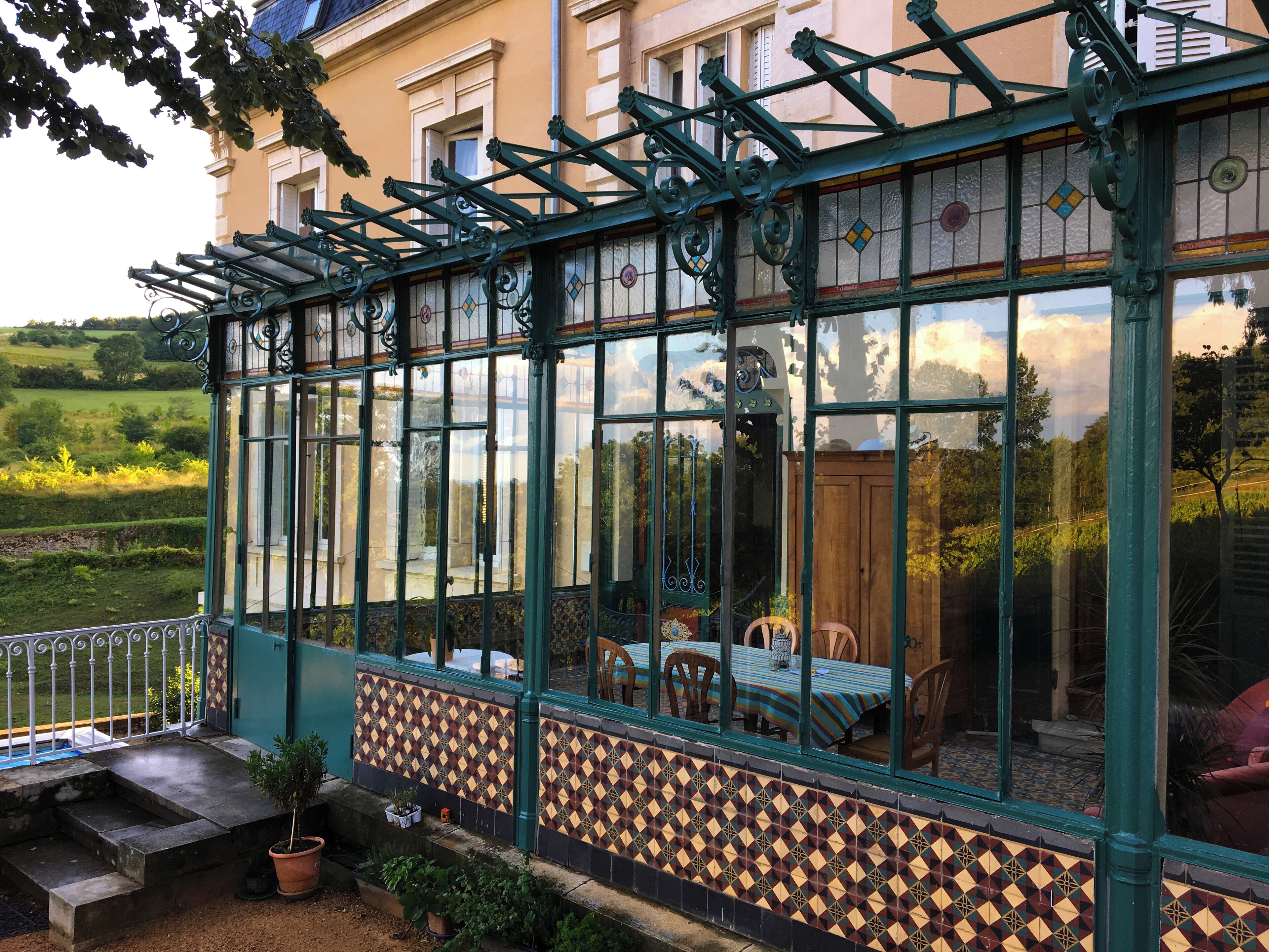 A conservatory with a tiled floor, a table with chairs, and a view of the garden.